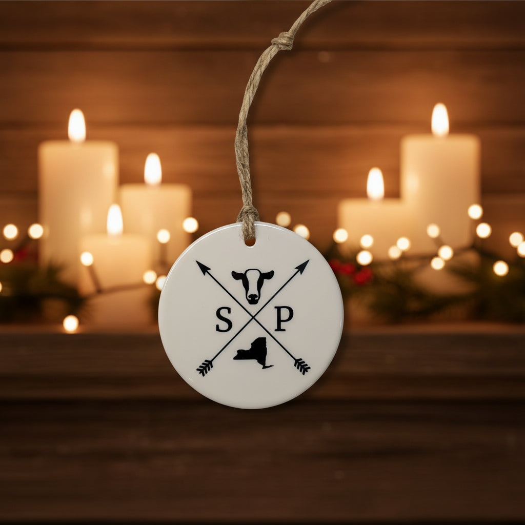 Round ceramic tag with cow and State silhouette and 'SP' initials on a white background