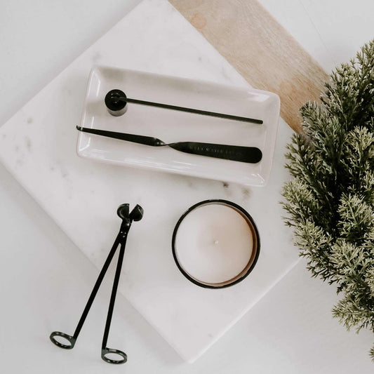 Black Candle Care Kit with matte black metal wick dipper, snuffer and trimmer beside a white candle.