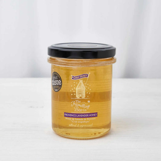 Honey jar of Provence Lavender Honey with amber golden honey, a clear glass container, black lid and printed label.
