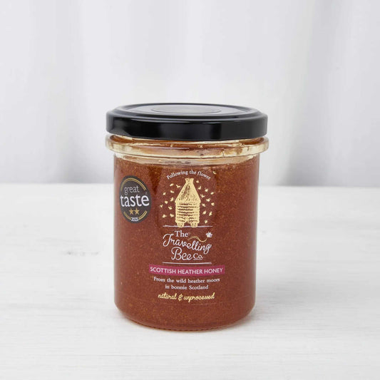 Scottish Heather Honey in a glass jar, deep amber-brown with a black lid and cream bee-themed label.