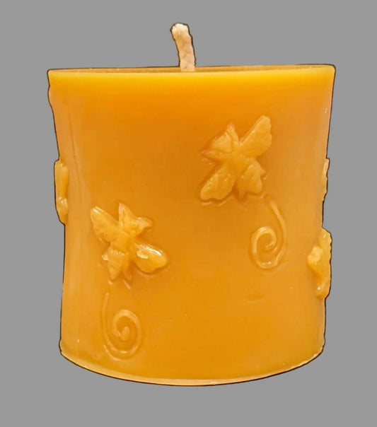 Pillar beeswax candle in golden orange with raised bee motifs and curling swirls; BEESWAX CANDLES : PILLAR WITH BEES