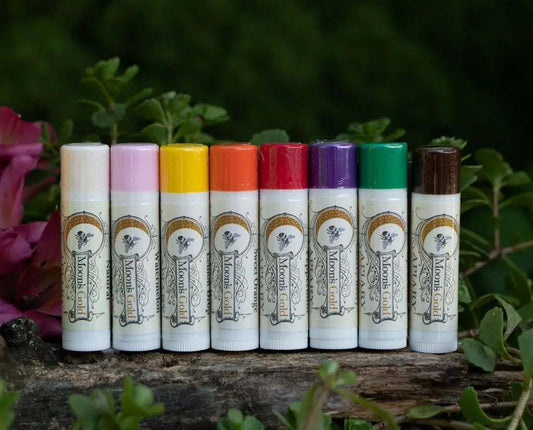 LIP BALMS in white cylindrical tubes with colorful caps, featuring a botanical label and small bird illustration.