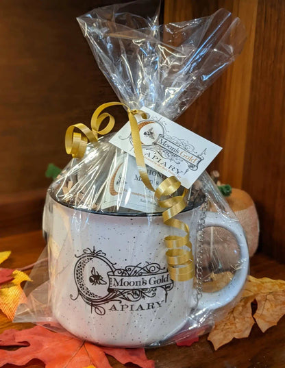 TEA FOR one ceramic mug set, white with black speckles and ornate black Moon’s Gold Apiary lettering, wrapped with a gold ribbon.